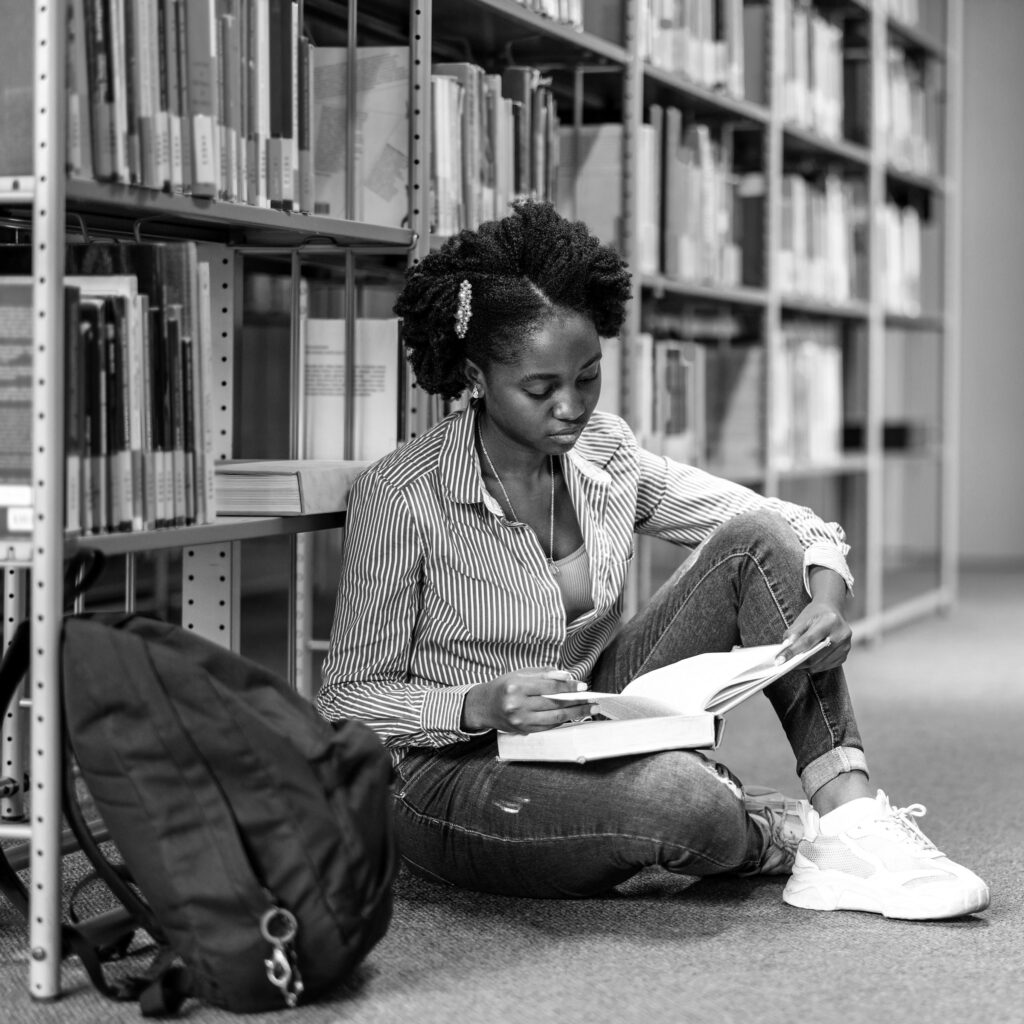 Student sitting on library floor reading